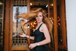 Fashion model posing outdoors against old fashion door looks at camera. Redhead German girl