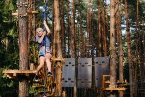 A girl passes an obstacle in a rope town. A girl in a forest rope park